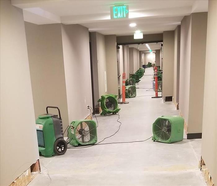 Photo is showing a commercial building hallway with SERVPRO green drying equipment placed throughout the hallway