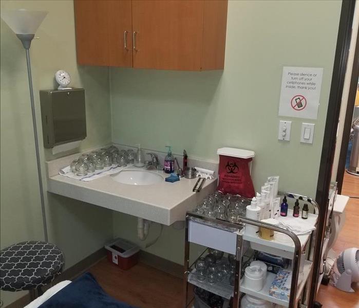 Patient Room in a Doctor's office, showing a sink, cabinet, standing light fixture, and a cart full of medical supplies