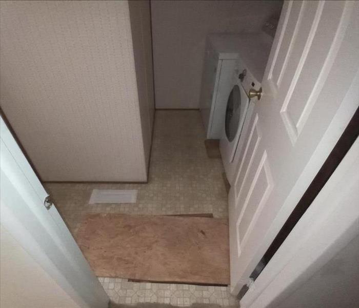 Photo is showing a laundry room in which the flooring has been removed due to water damage. 