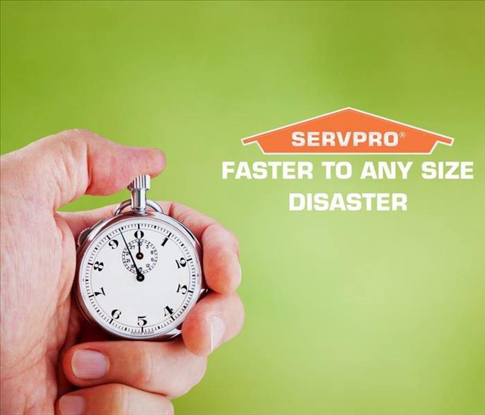 Photo is showing a man's hand holding a stop watch with the SERVPRO house logo to the right of his hand