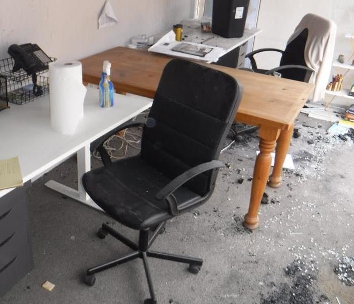 Photo is showing office desks and office chairs with soot from a fire