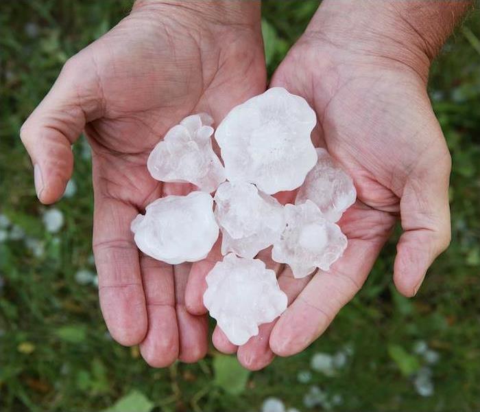 Photo is showing hail (big pieces of ice) being held in the palm of someone's hands. 