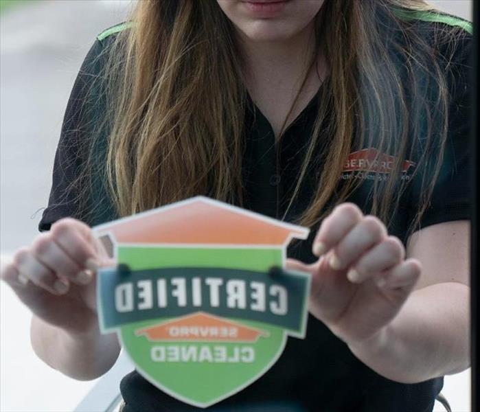 Photo is showing a SERVPRO employee placing a Certified: SERVPRO Cleaned sticker on someone's business window